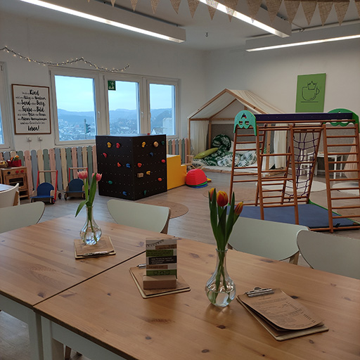 Lichtdurchfluteter Kinderraum mit Spielgeräten und Tischen