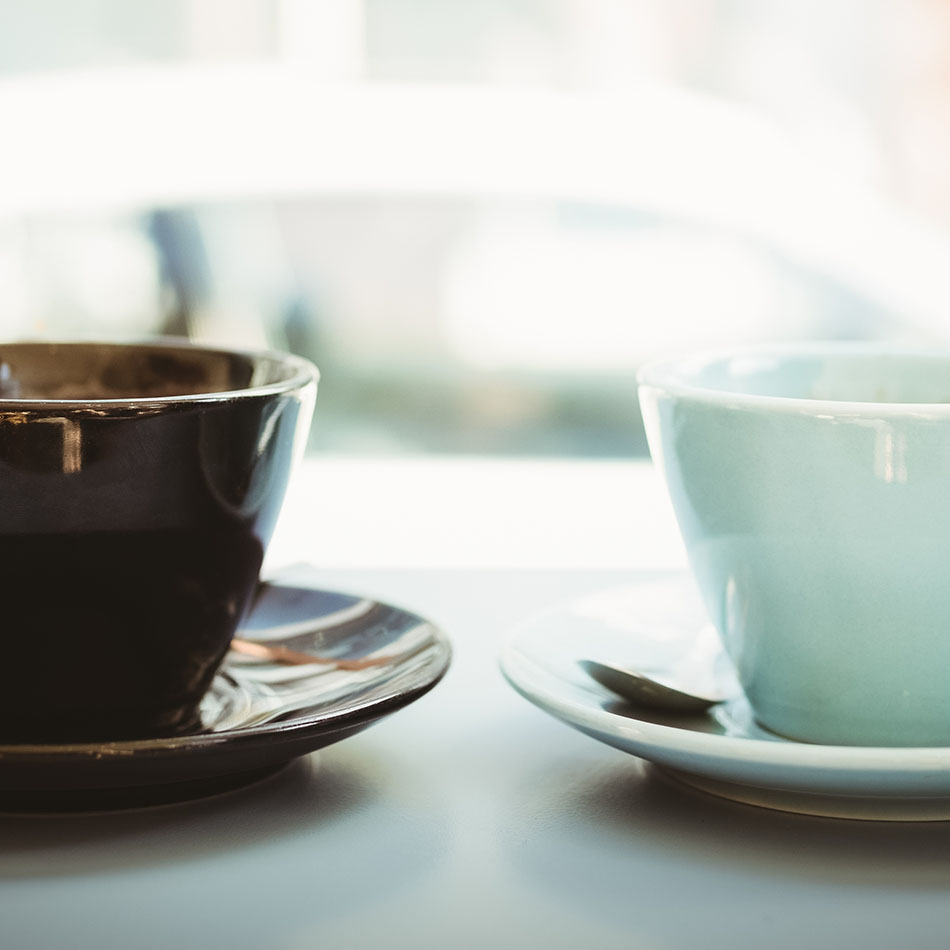 Zwei Kaffeetassen auf einem Tisch am Fenster