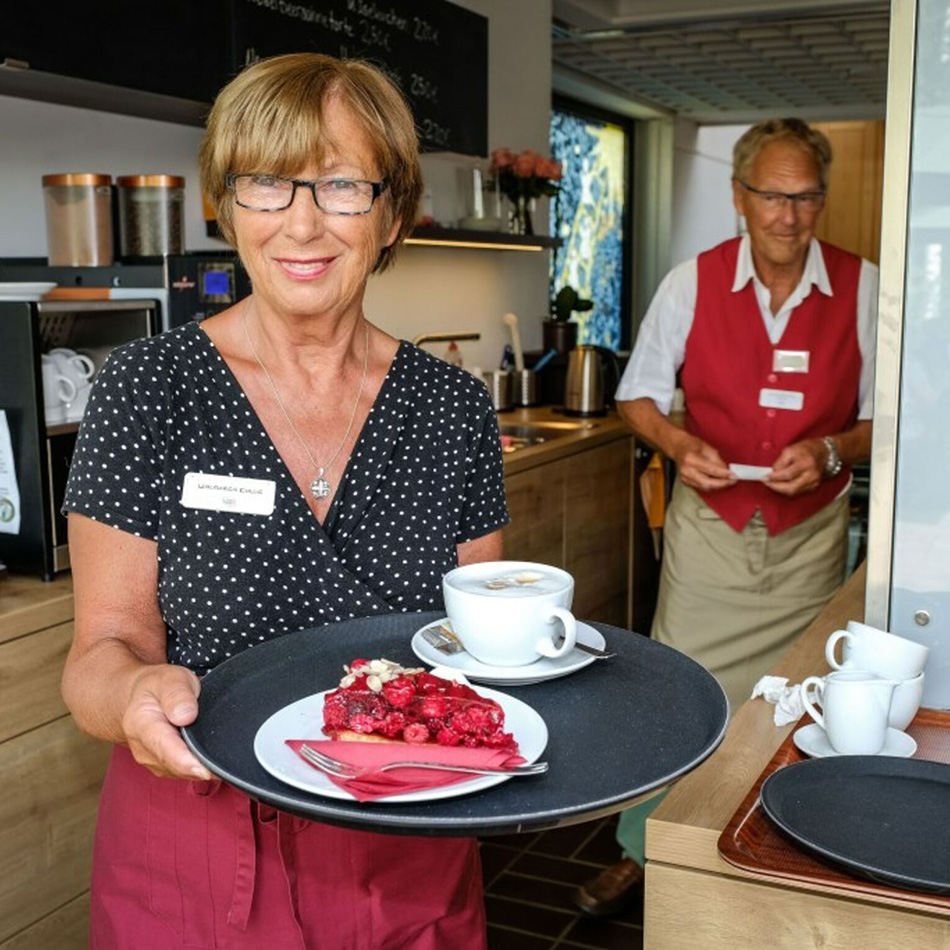 Frau serviert Kaffee und Kuchen im Café.