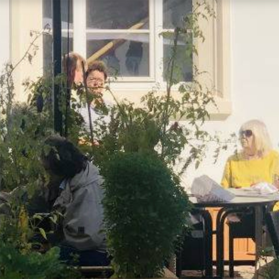Menschen genießen sonnigen Tag im Gartenrestaurant.